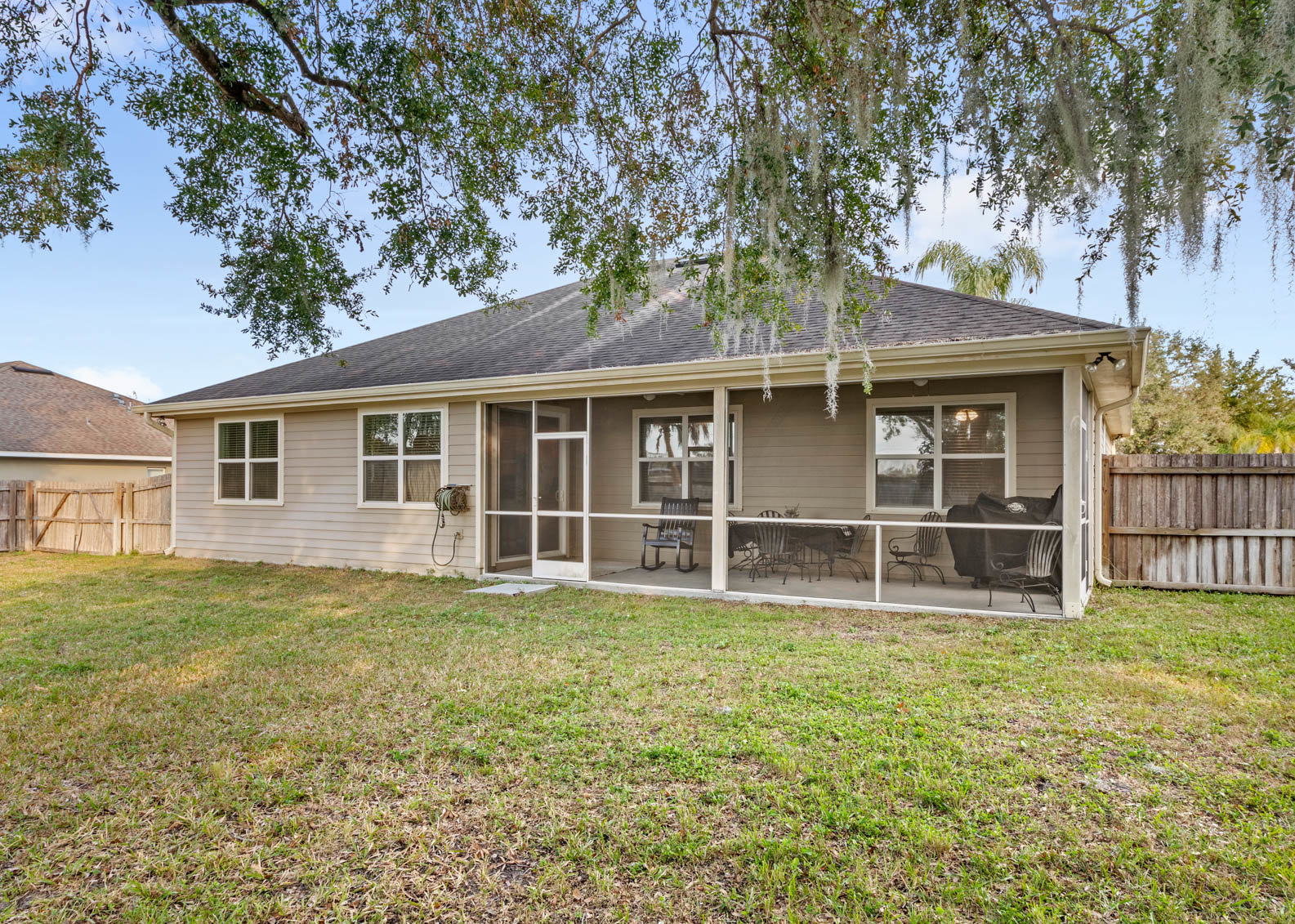 back of home with yard and view of screened in patio